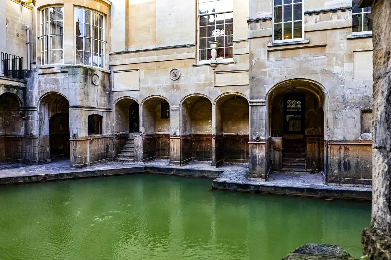 The colonnade above the green water of the Roman Baths in Bath