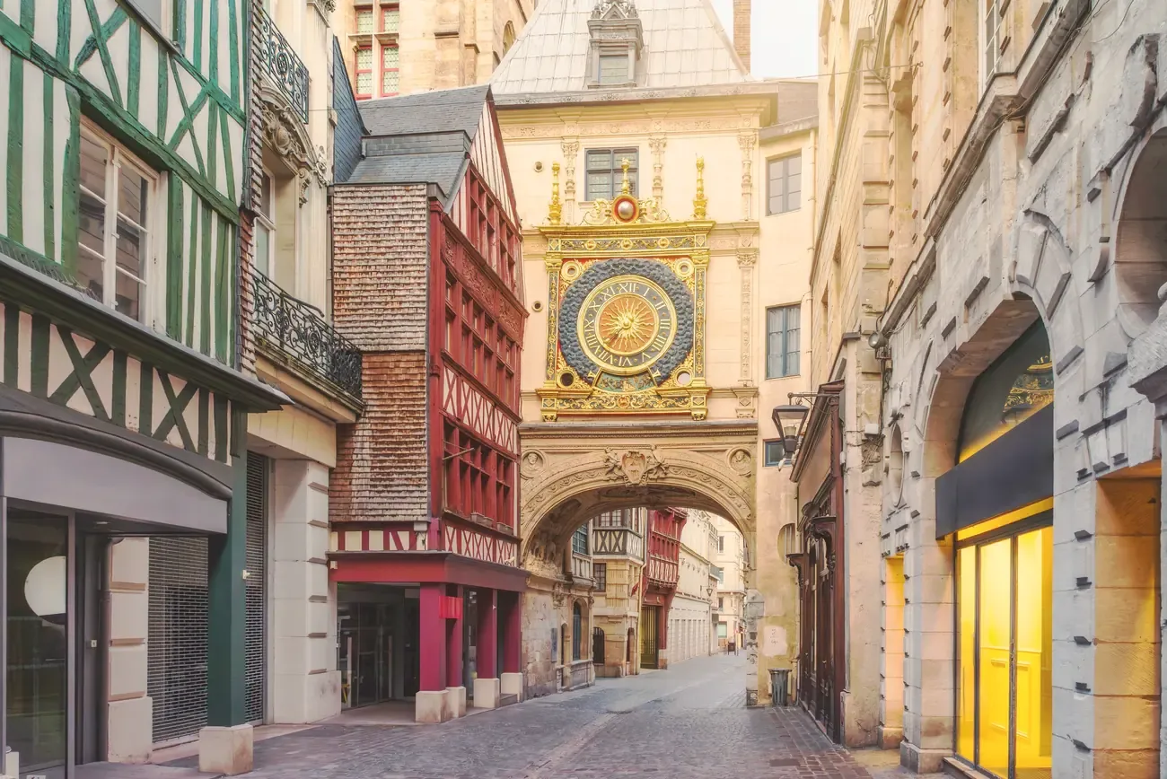 The Gros Horloge clock tower above a medieval street in Rouen at dusk, France