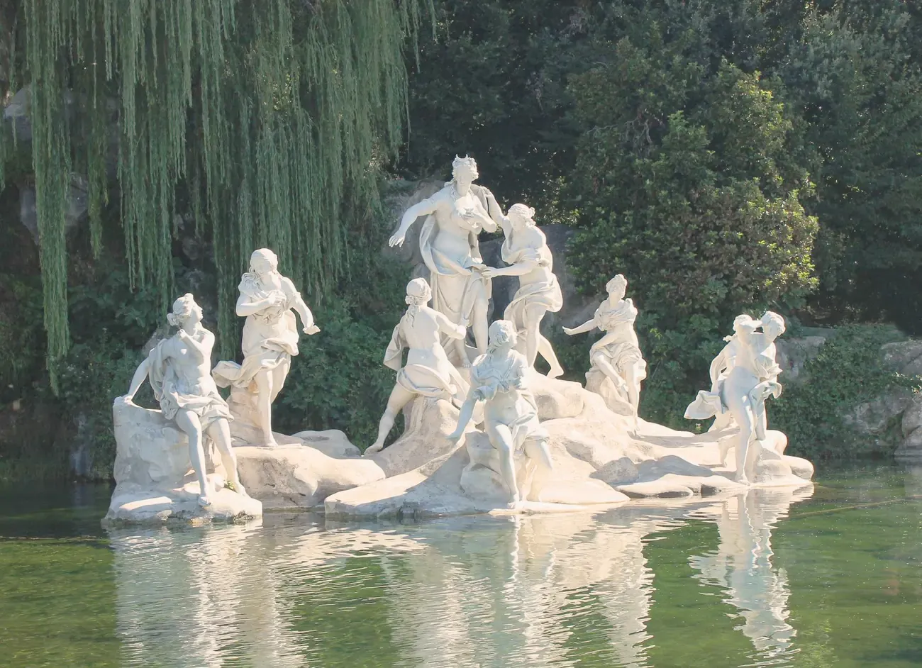 Marble nymph statue group reflected in a garden pond at the Royal Palace of Caserta