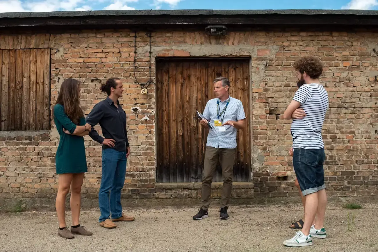 A guide briefing a small group outside a barrack building at Sachsenhausen Memorial