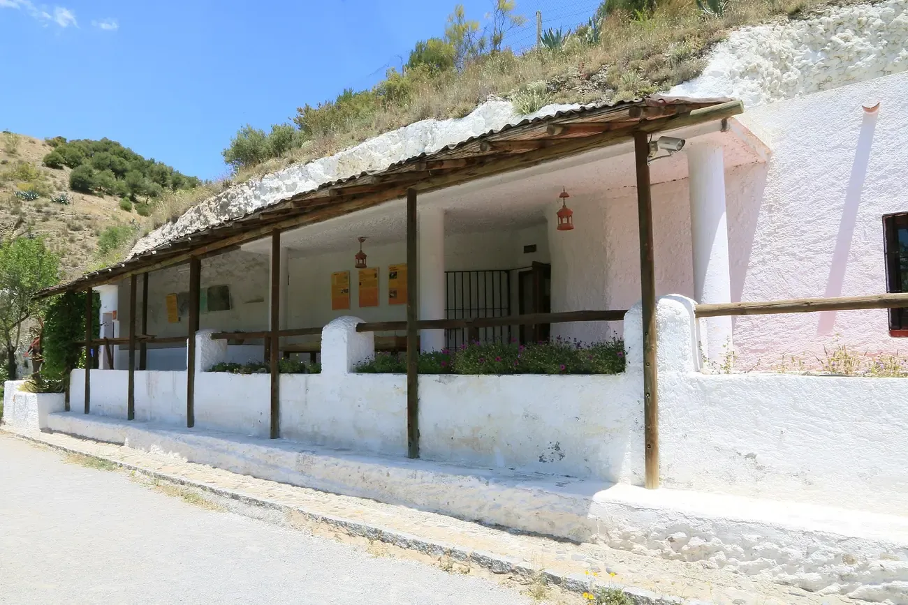 Whitewashed cave dwelling with a covered porch dug into the hillside at the Sacromonte Caves Museum in Granada