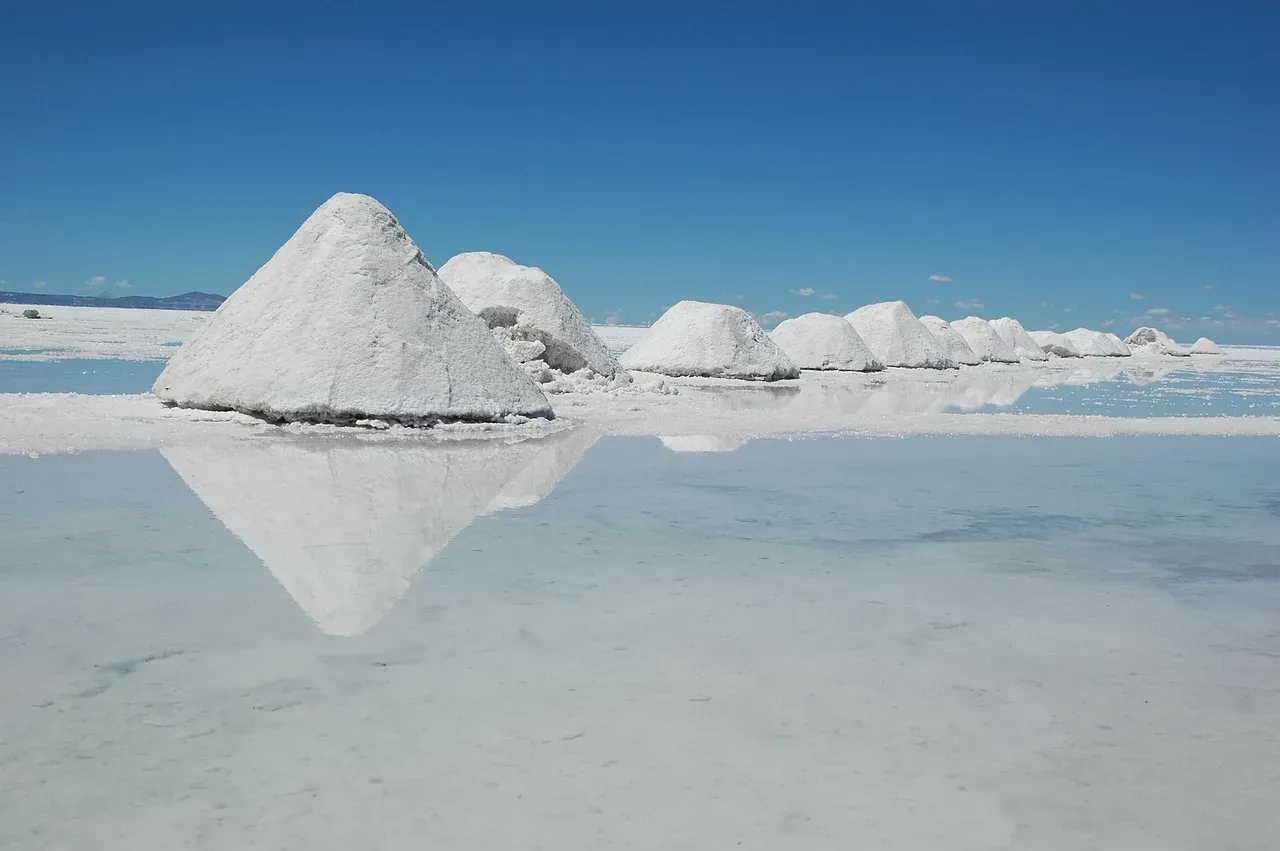Mounds of harvested salt reflected in a thin sheet of water on the Salar de Uyuni