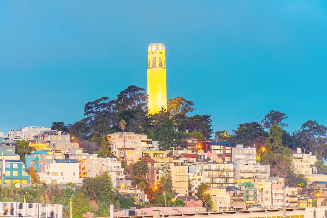 Coit Tower illuminated at twilight above San Francisco