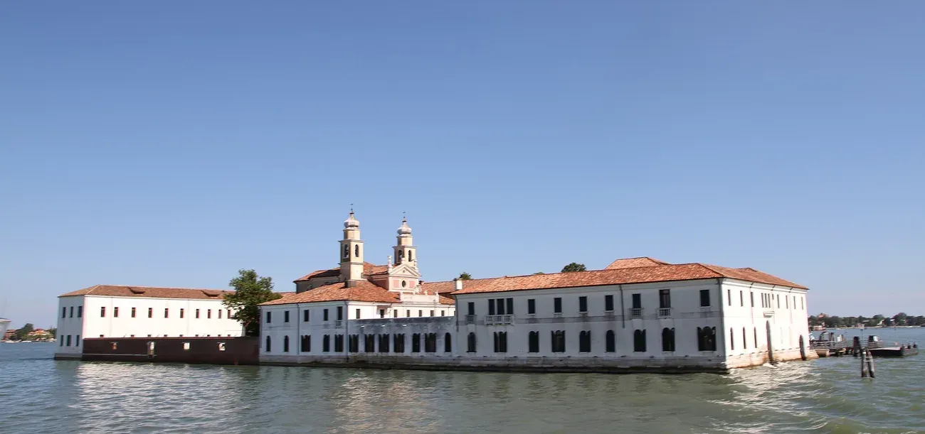 The white buildings and twin bell towers of San Servolo island in the Venetian lagoon, home of the former asylum and its museum
