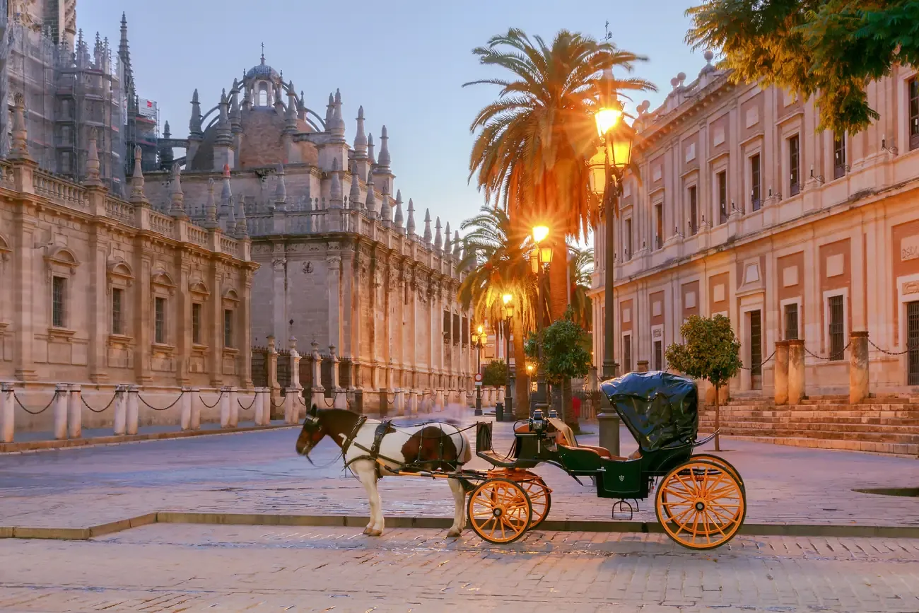 Seville Cathedral with a horse carriage at dawn