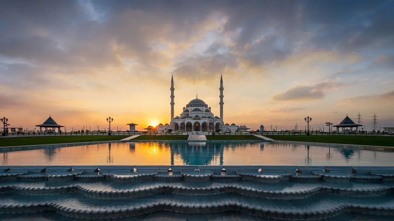 The Sharjah Mosque reflected in the pool waters at sunset