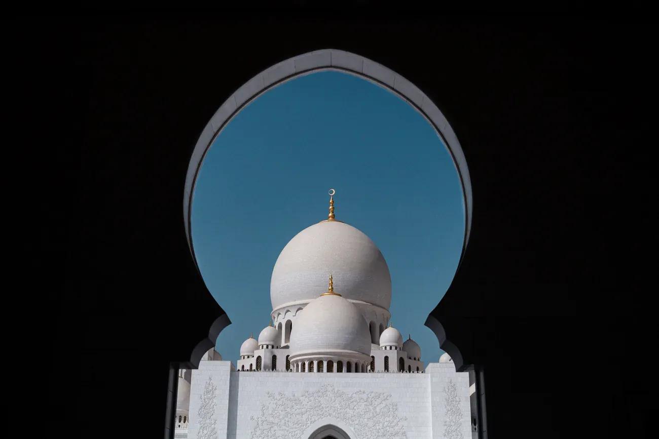 A dome of Sheikh Zayed Grand Mosque framed by an arch at night, Abu Dhabi