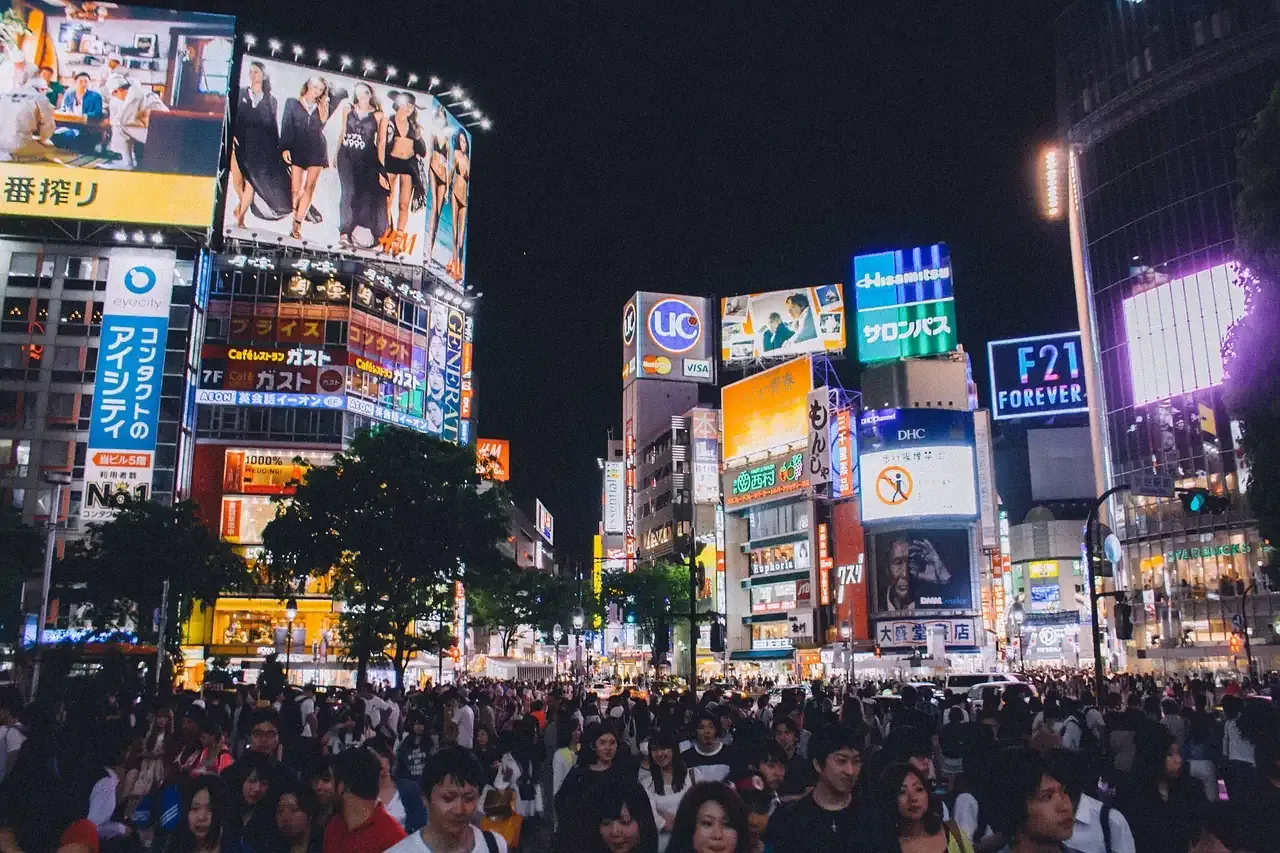 Crowds on the Shibuya crossing under neon signs at night in Tokyo
