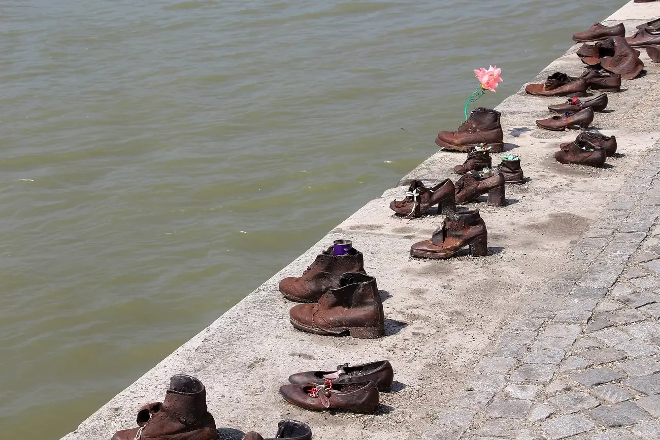 Rows of bronze-coloured iron shoes along the stone edge of the Danube embankment at the Shoes on the Danube Bank memorial in Budapest