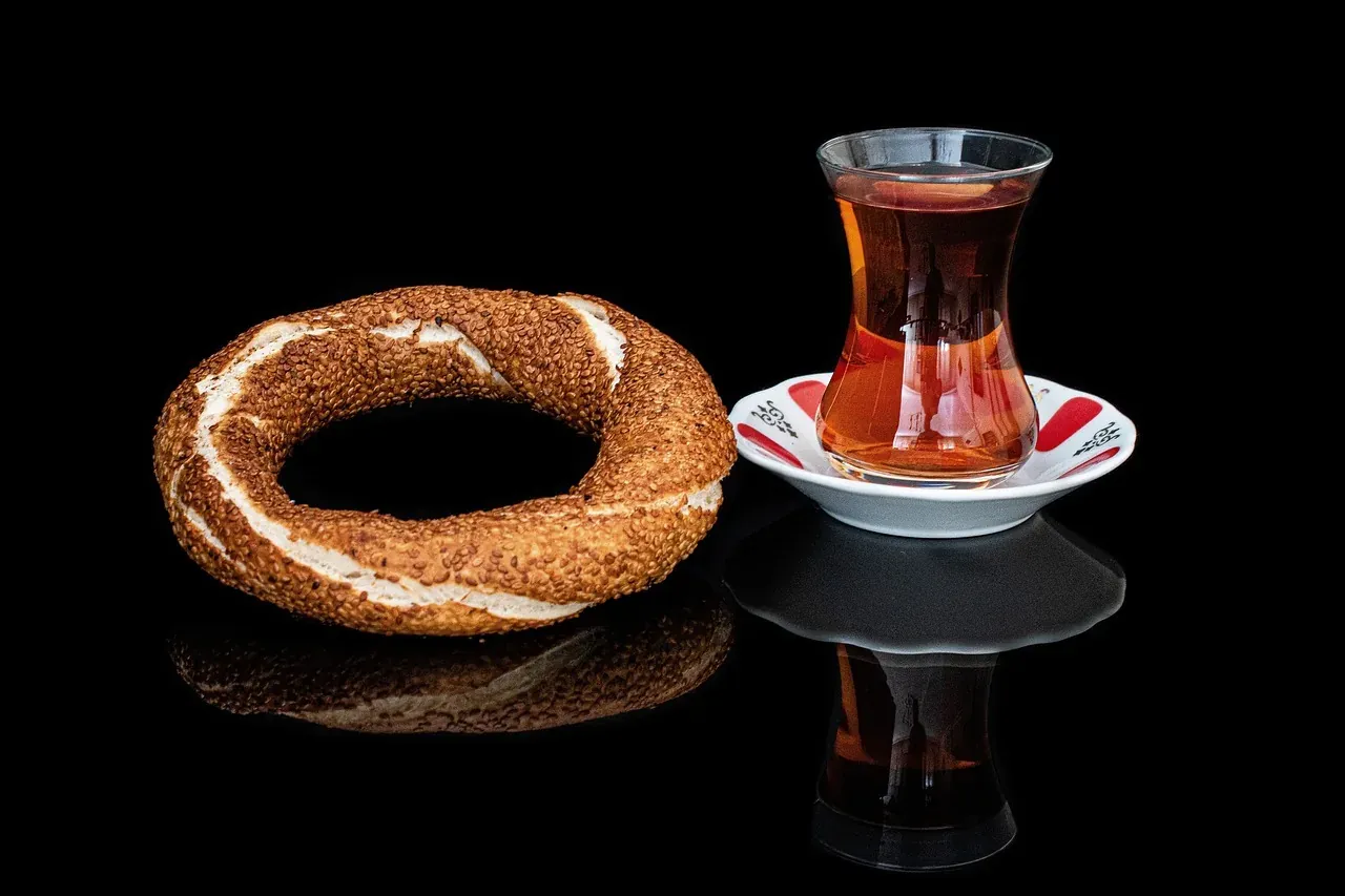 A sesame-crusted simit beside a glass of Turkish tea