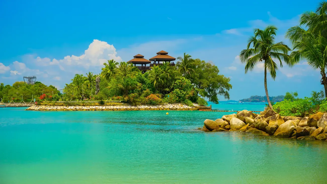 The palm-fringed islet and lookout towers at Palawan Beach on Sentosa Island, Singapore