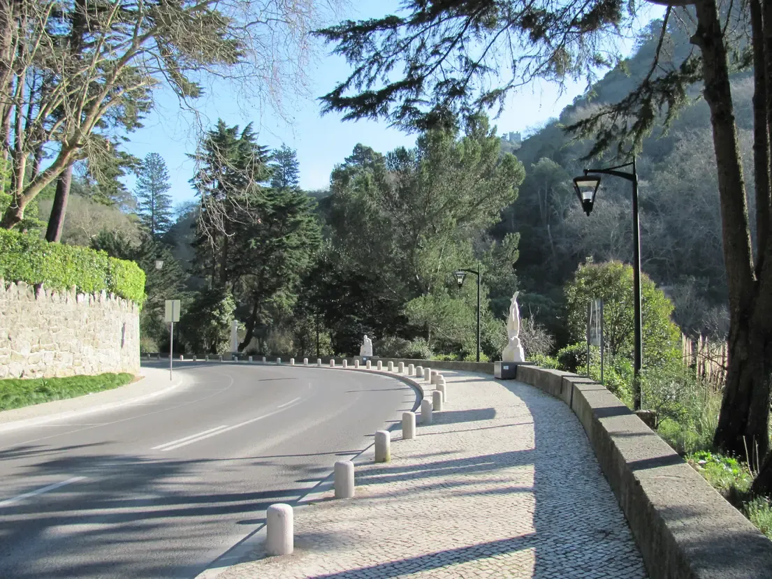The curving tree-lined Volta do Duche promenade in Sintra, with its cobbled walkway, lamp posts and sculptures