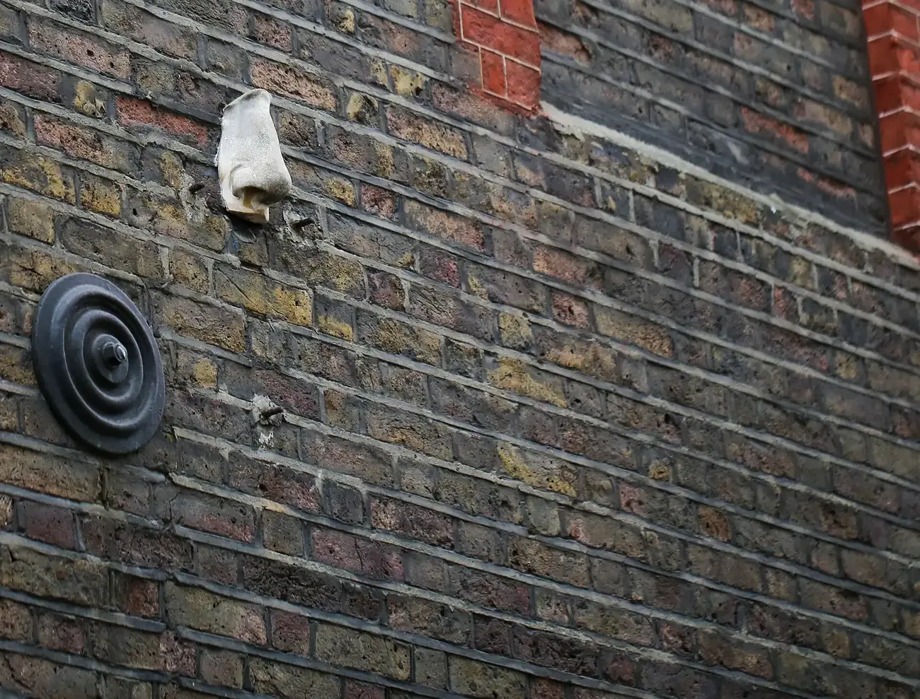 A plaster nose fixed high on a brick wall in Soho, one of the Seven Noses of Soho in London