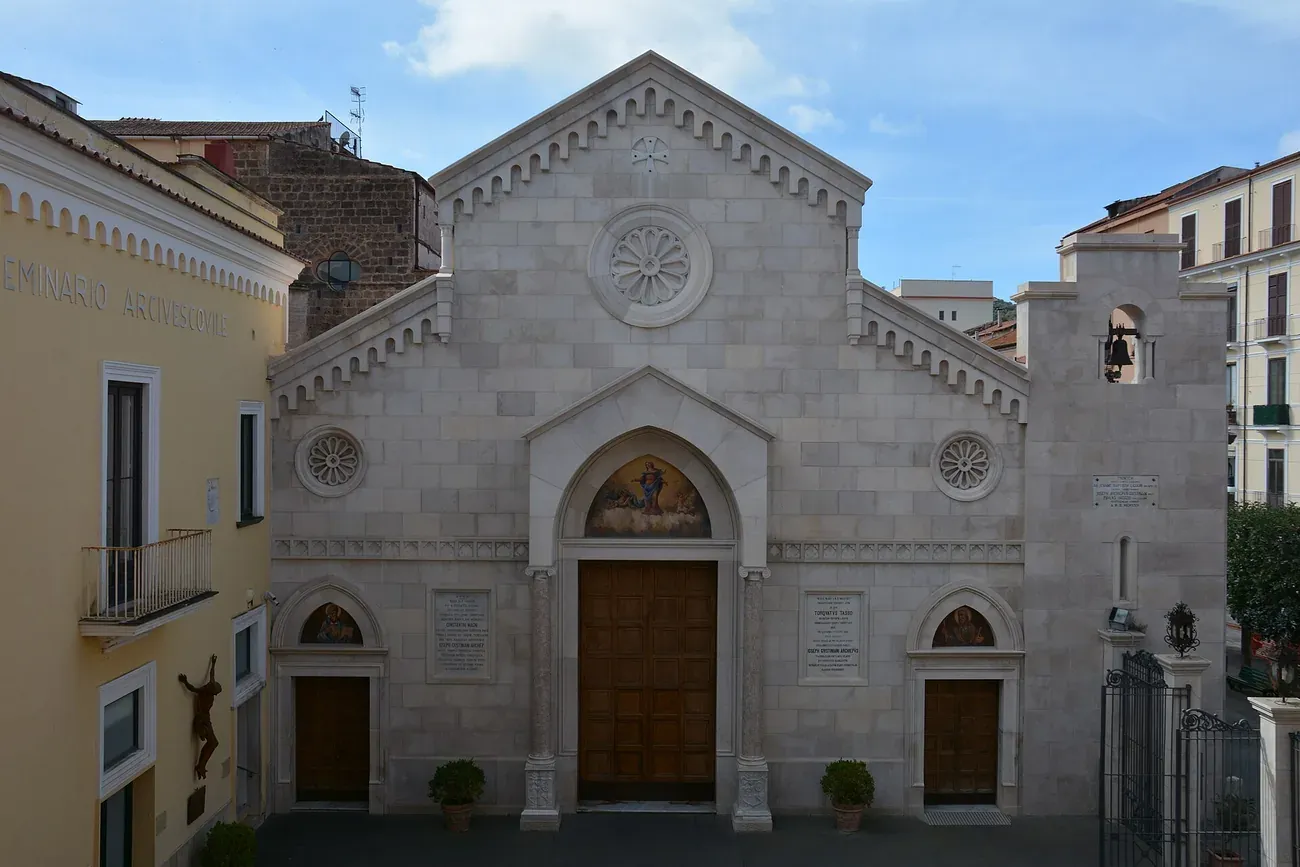 The white stone facade of Sorrento Cathedral, dedicated to Saints Philip and James, with its rose window and painted lunette over the door