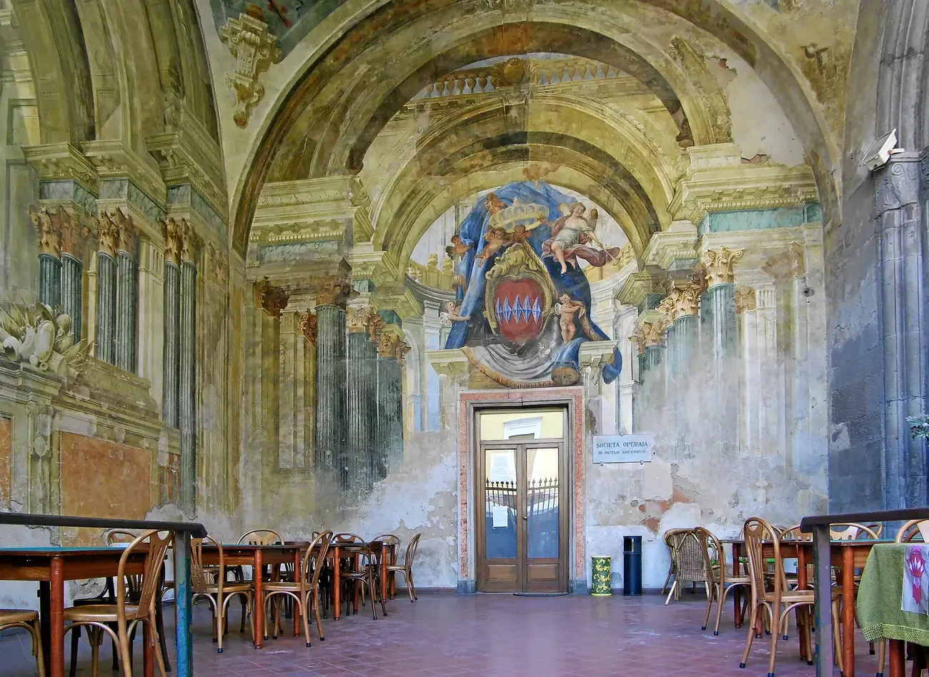 The frescoed loggia of the Sedile Dominova in Sorrento, with painted columns and a coat of arms above the door