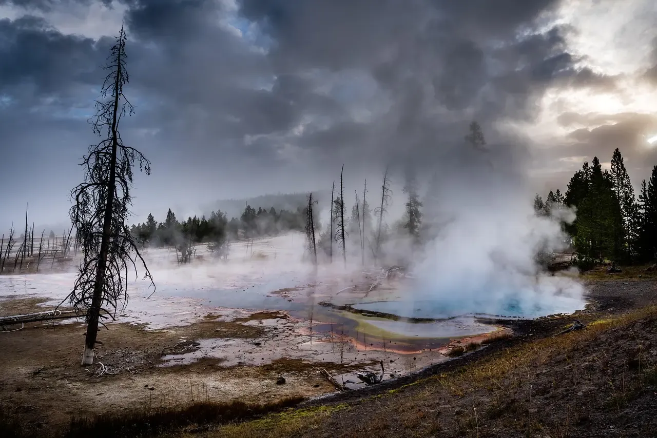 Steam rising from a geyser basin under storm clouds in Yellowstone, Wyoming