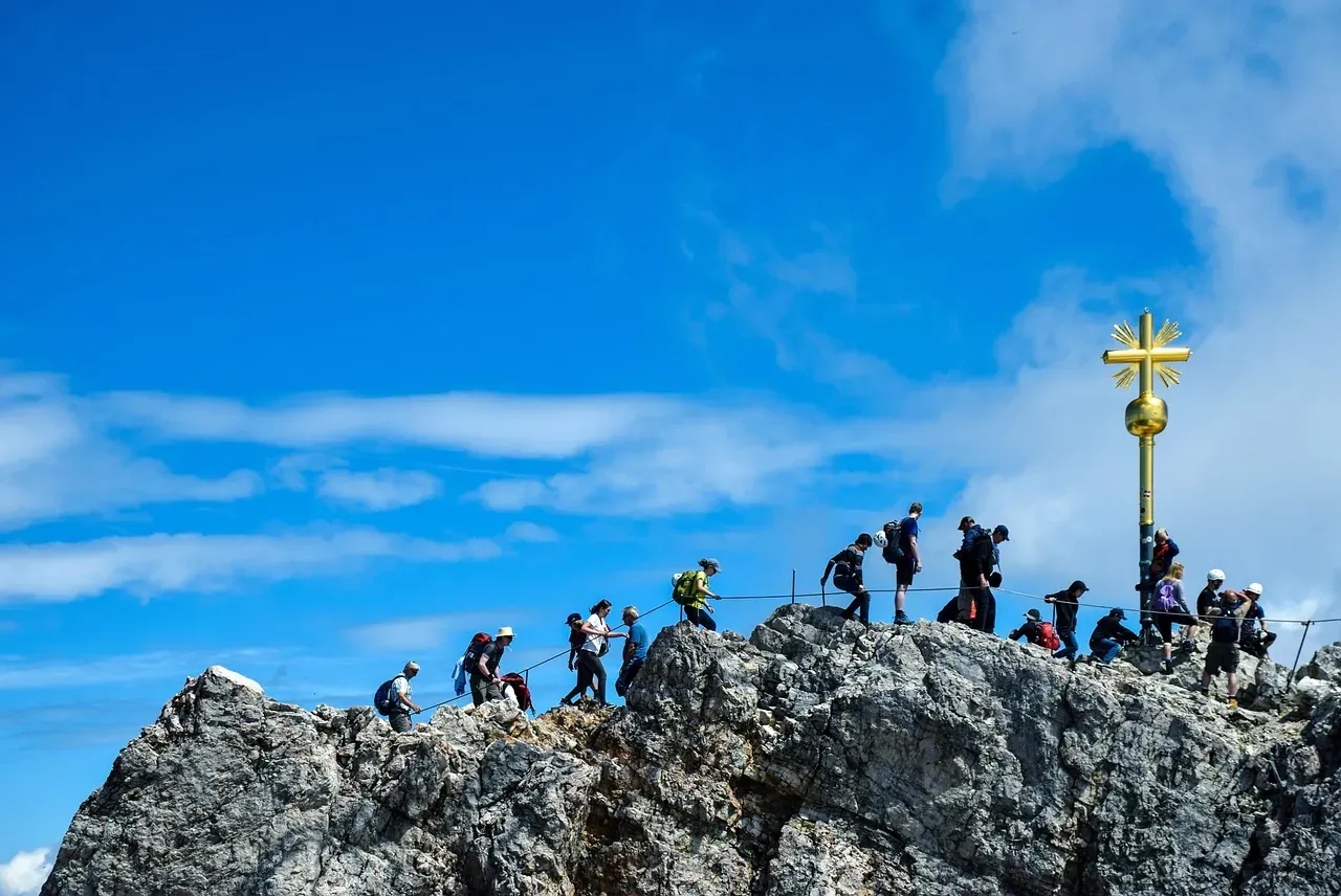 Walkers gathered at the golden summit cross on the Zugspitze above Garmisch-Partenkirchen