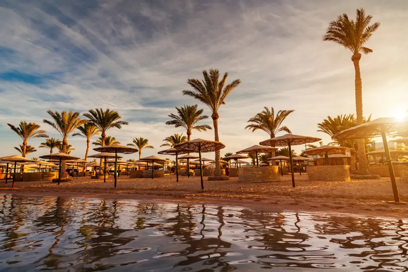 Sunset over a sandy beach with palm trees in Hurghada, Egypt