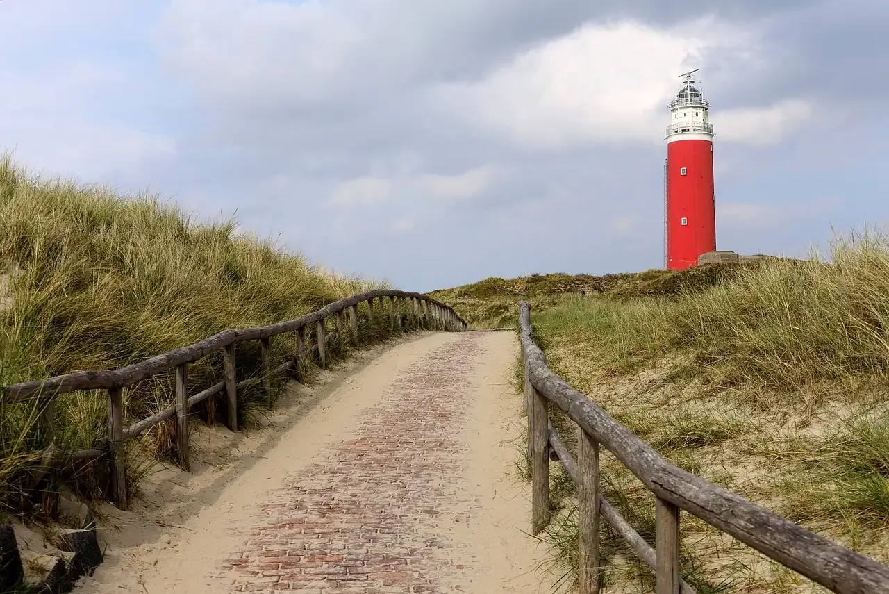 The red Eierland lighthouse rising above a dune path on the island of Texel