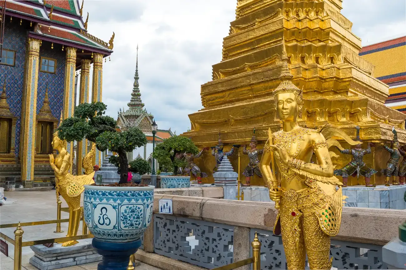 Golden guardian statue and gilded chedi inside the Grand Palace complex.