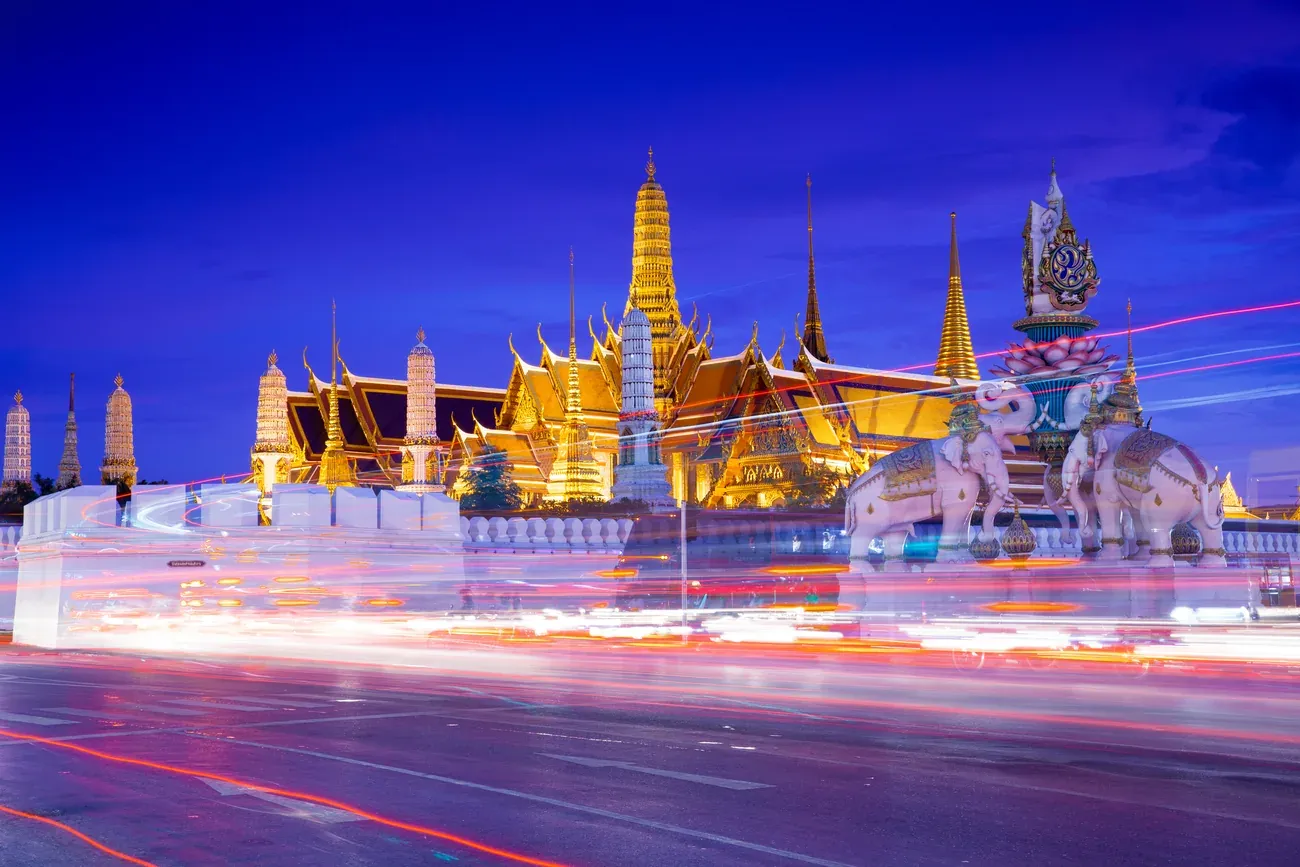 Street traffic passing near the Grand Palace walls in Bangkok.