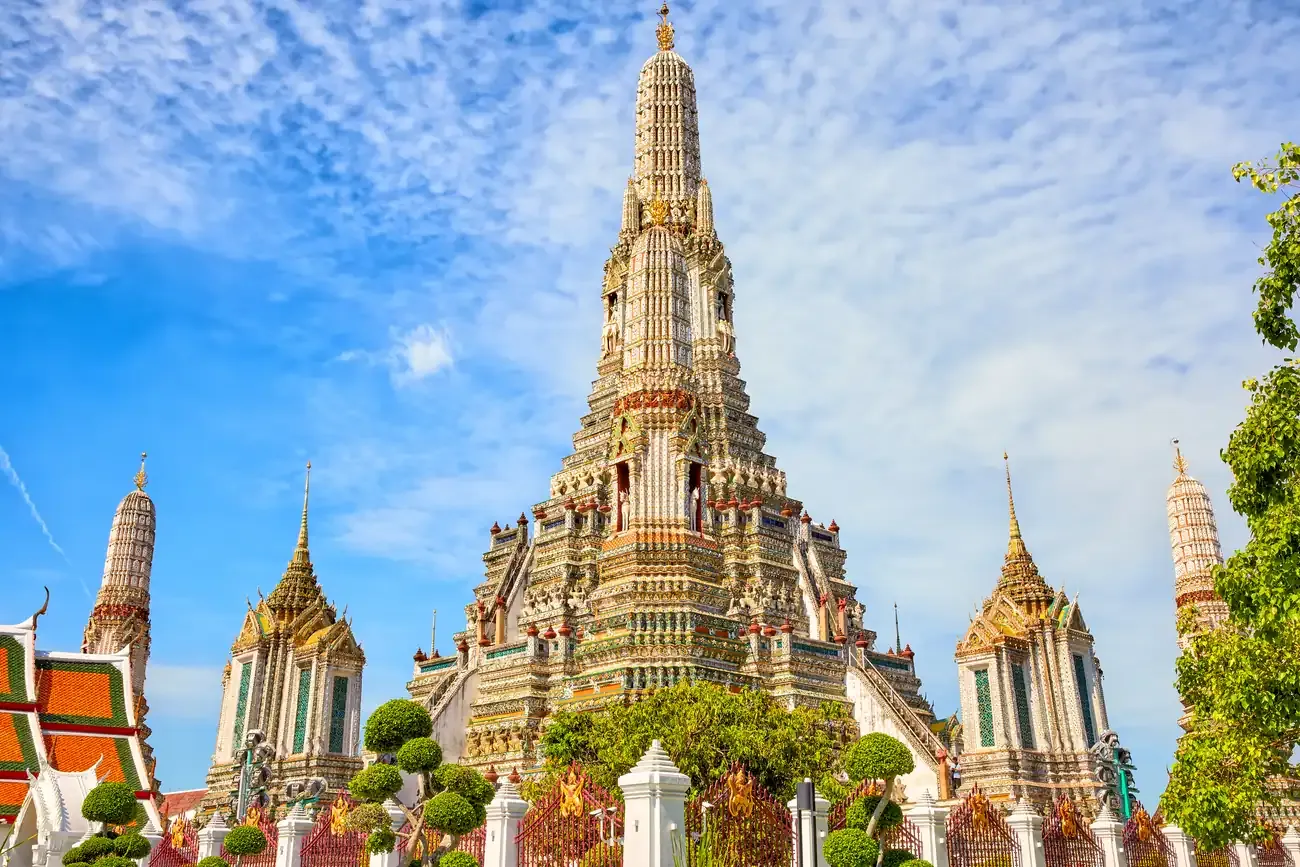 Wat Arun's central spire and surrounding stupas under a blue sky.