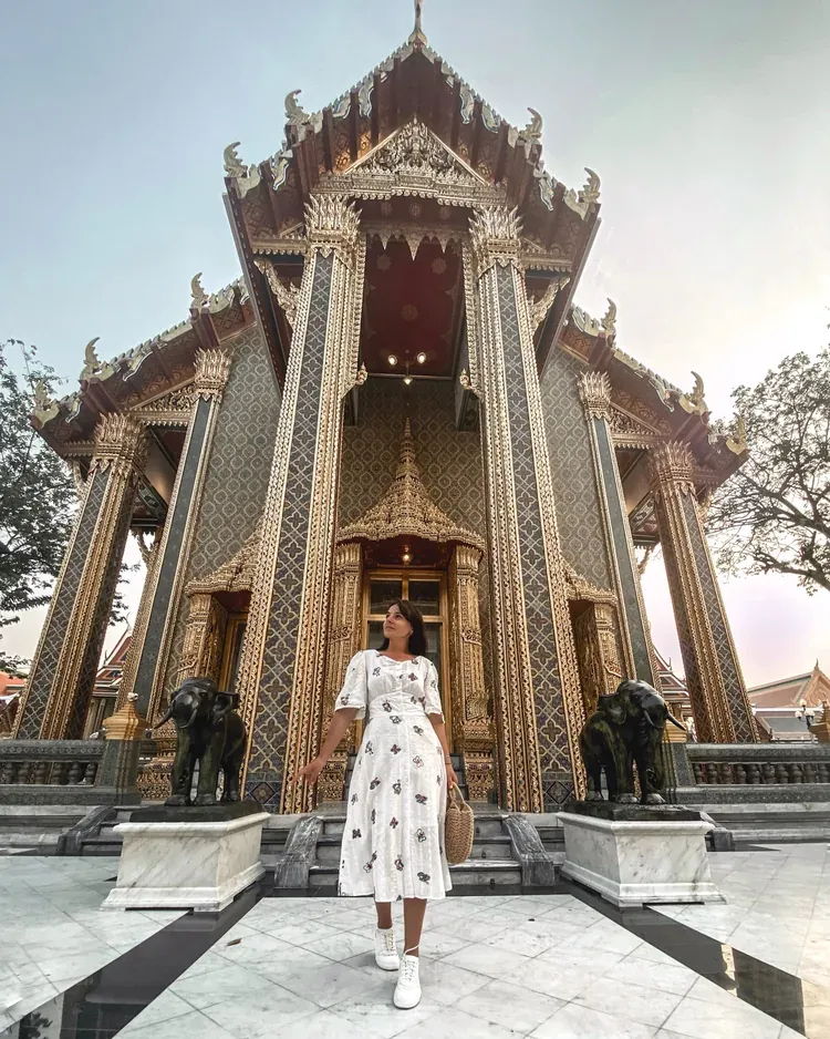 A visitor at the entrance of an ornate Bangkok temple.
