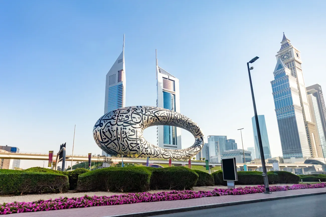 The Museum of the Future with the Emirates Towers and clock tower behind it.