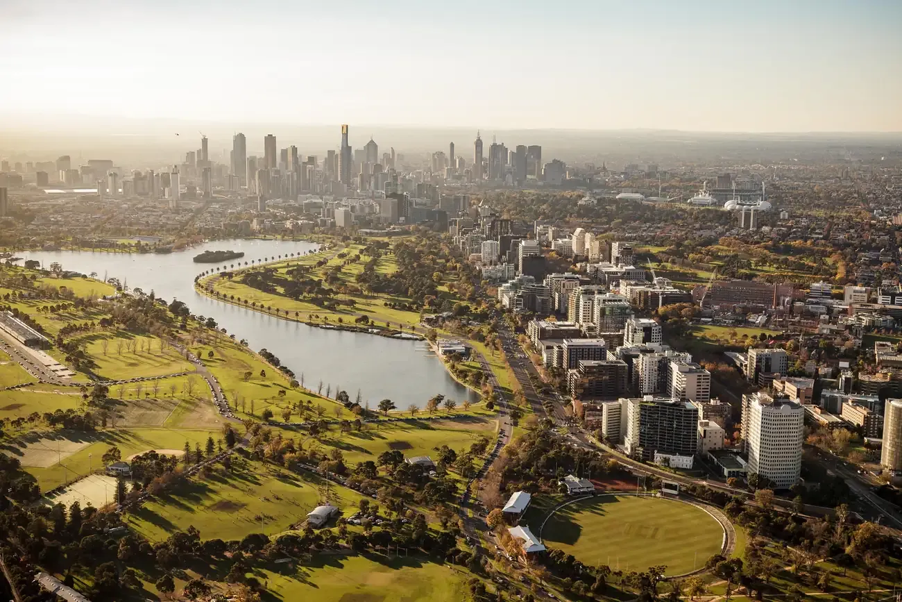 Aerial view over Albert Park lake and its parkland towards the Melbourne skyline
