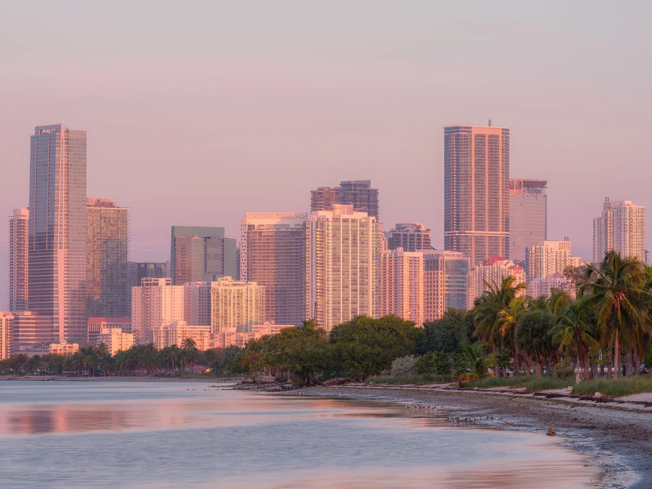 Downtown Miami towers catching pink light at sunrise across the bay
