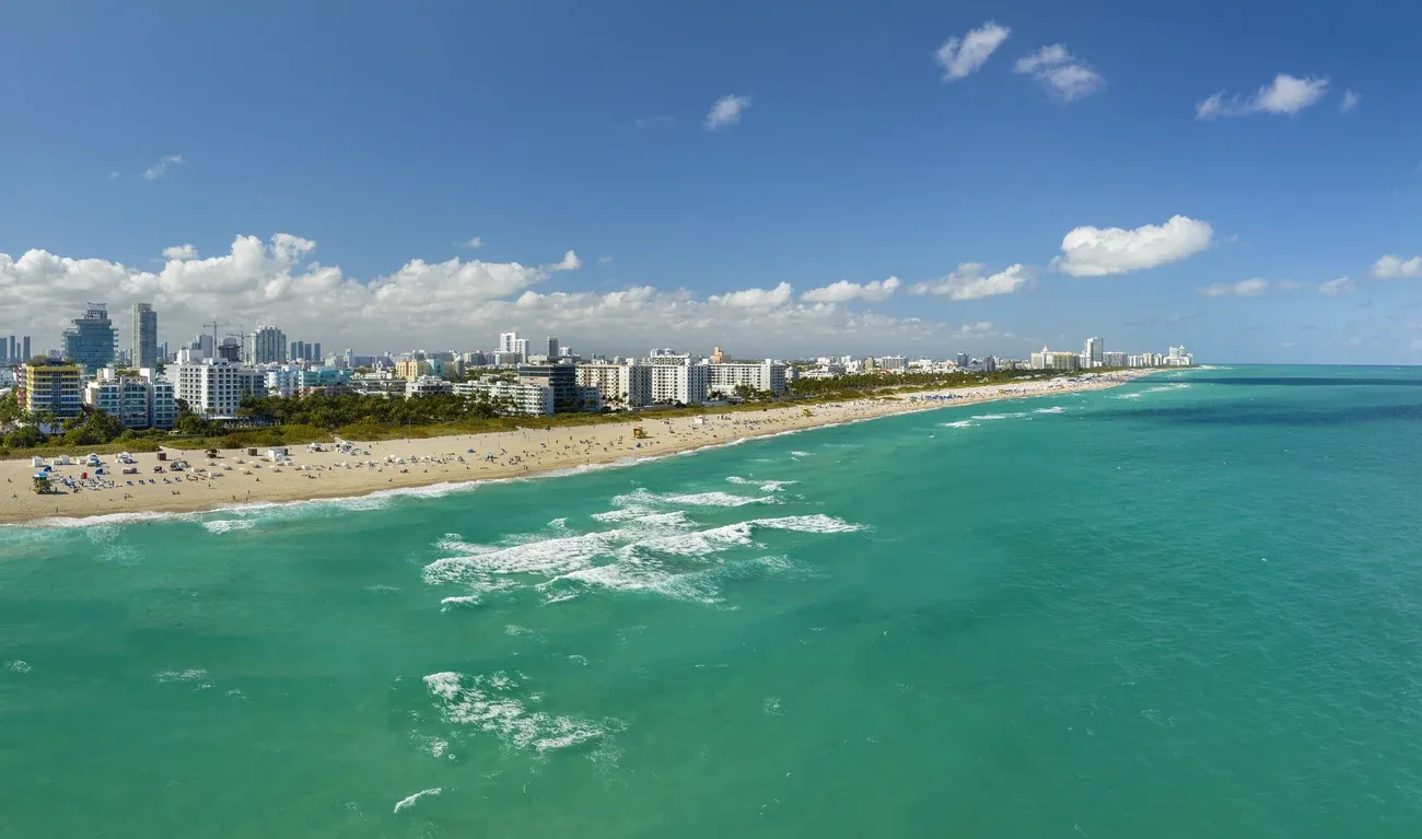 Turquoise water breaking along the wide sand of South Beach in Miami
