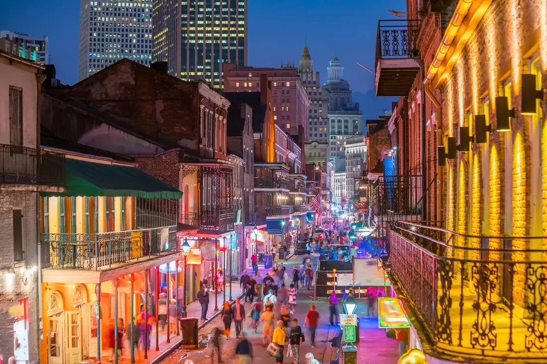 Neon signs and crowds along Bourbon Street after dark