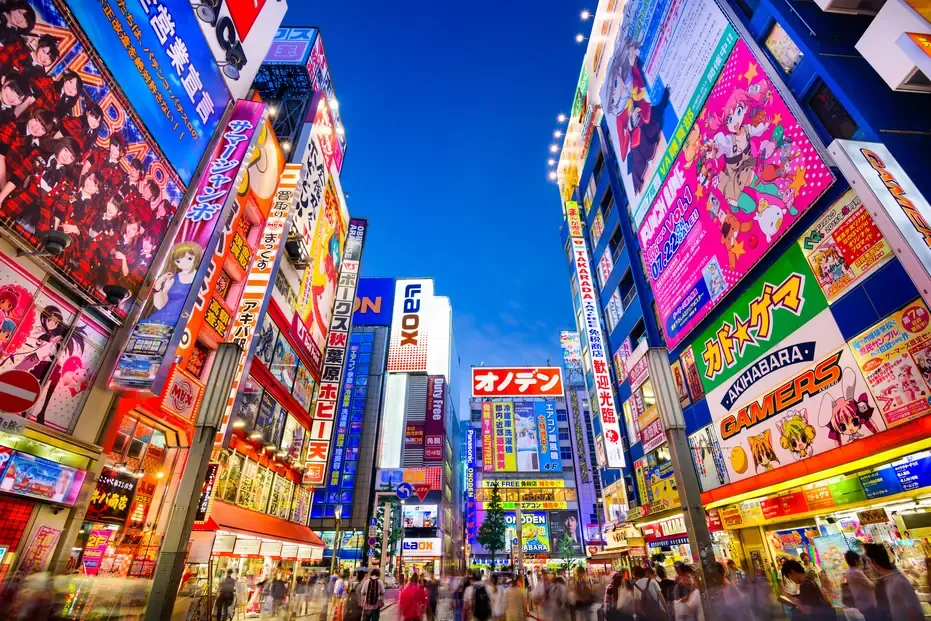 Stacked neon signs and shopfronts of Akihabara at dusk