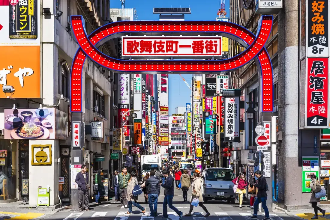 Pedestrians crossing under the red Kabukicho gate in Shinjuku