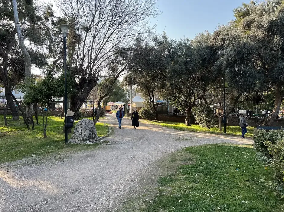 Visitors walking along the gravel path through Thiseio park beside the Ancient Agora in Athens