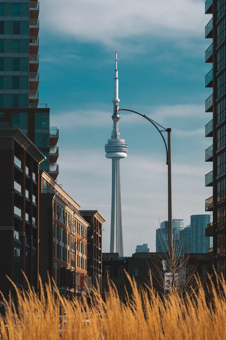 The CN Tower rising at the end of a street lined with brick buildings in Toronto