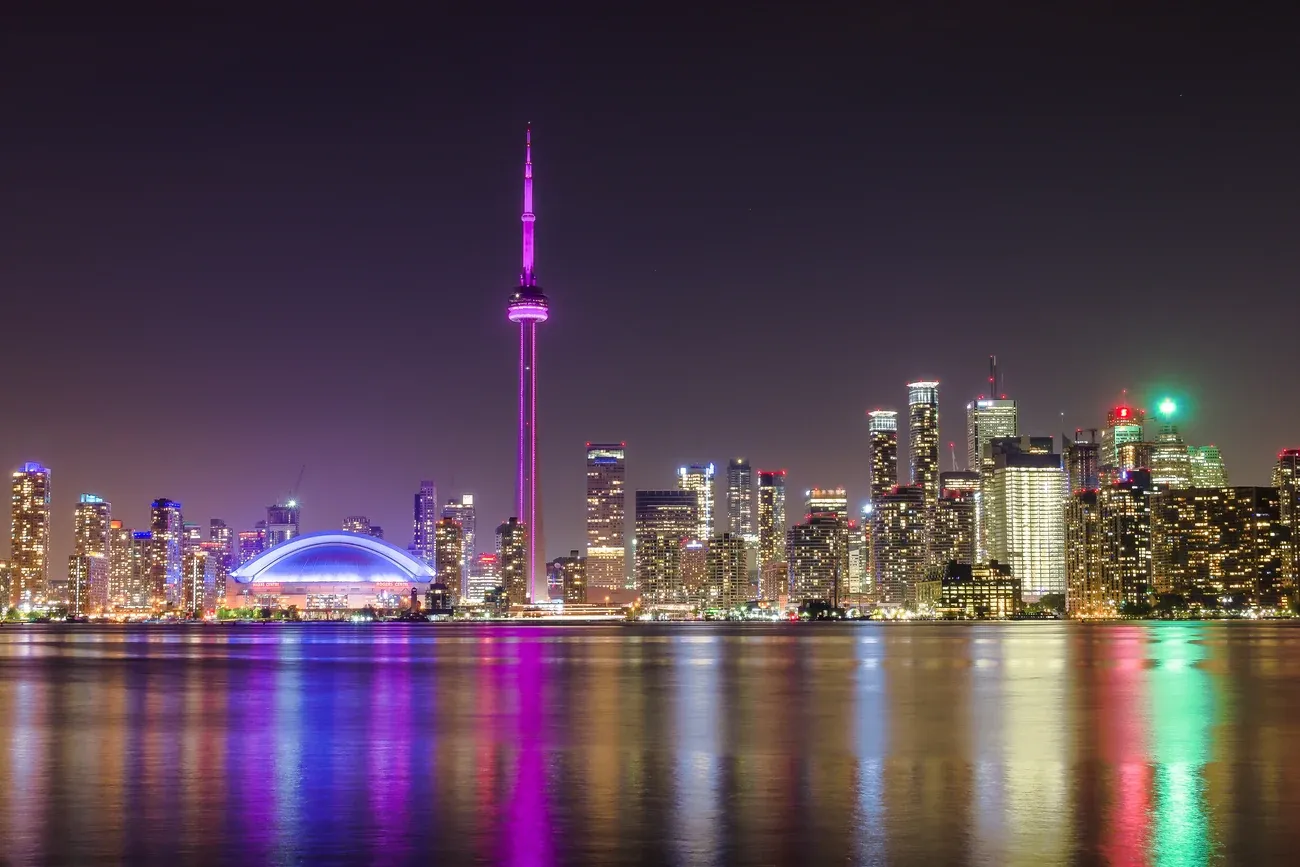 The lit Toronto skyline and CN Tower reflected in Lake Ontario at night