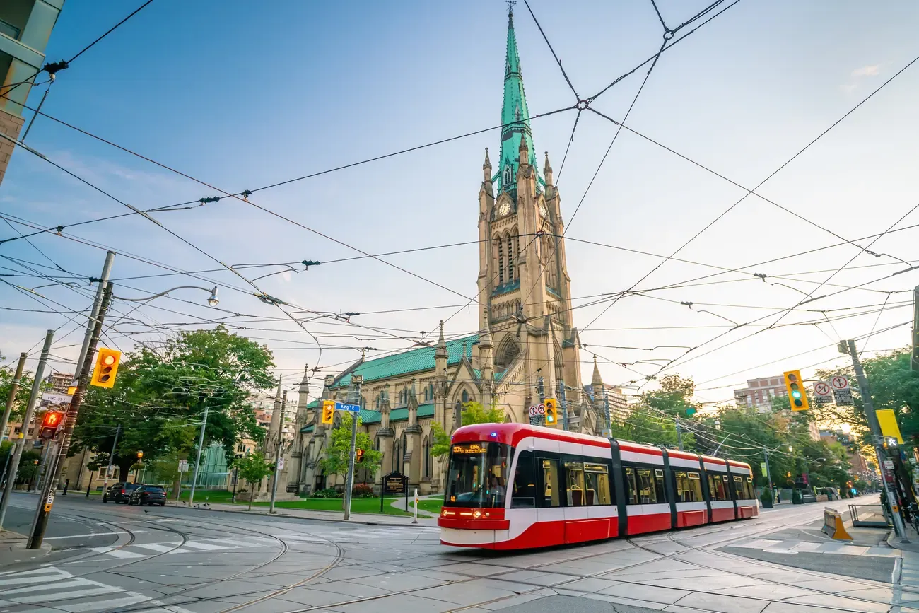 A red streetcar passing the spire of St James Cathedral in downtown Toronto