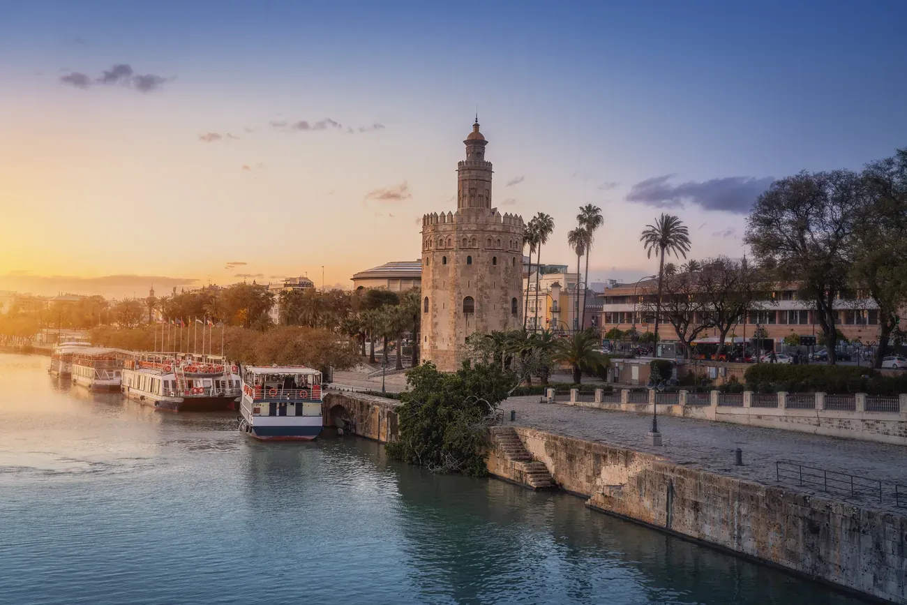 The Torre del Oro beside the Guadalquivir river with boats at sunset, Seville