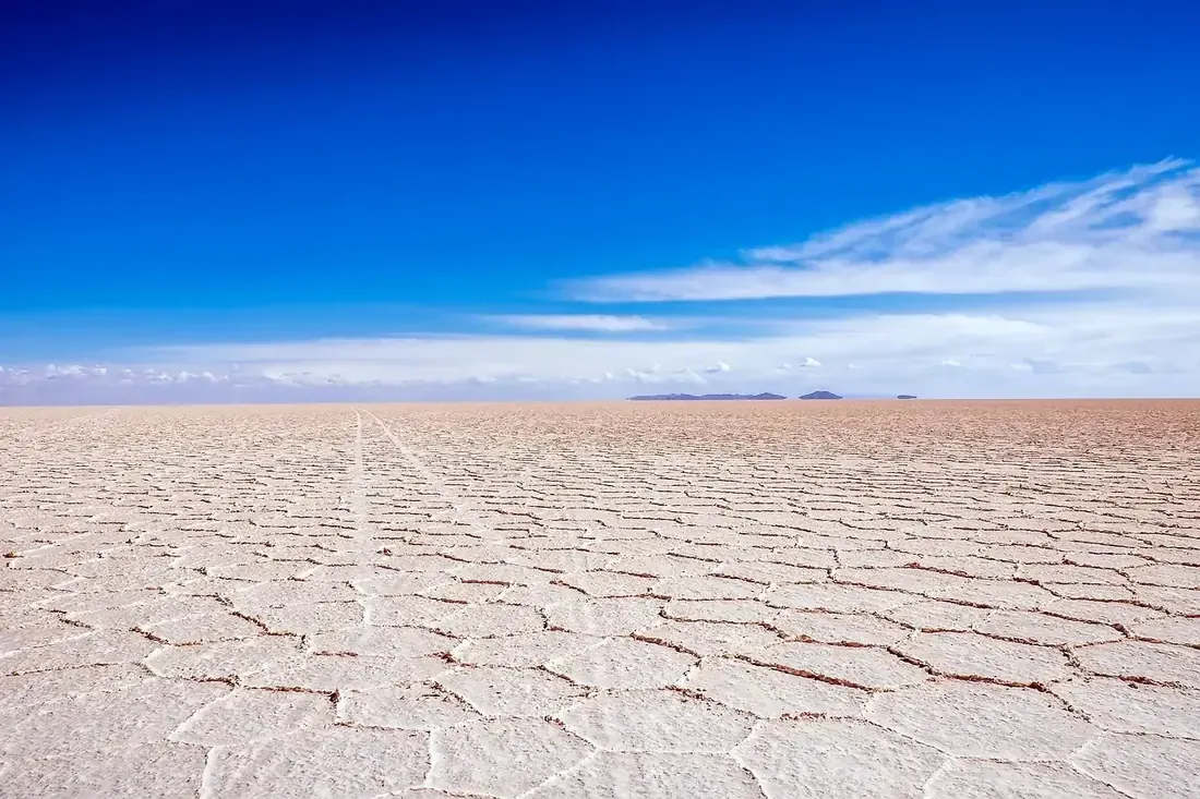 Vehicle tracks running across the hexagonal crust of the Salar de Uyuni, Bolivia