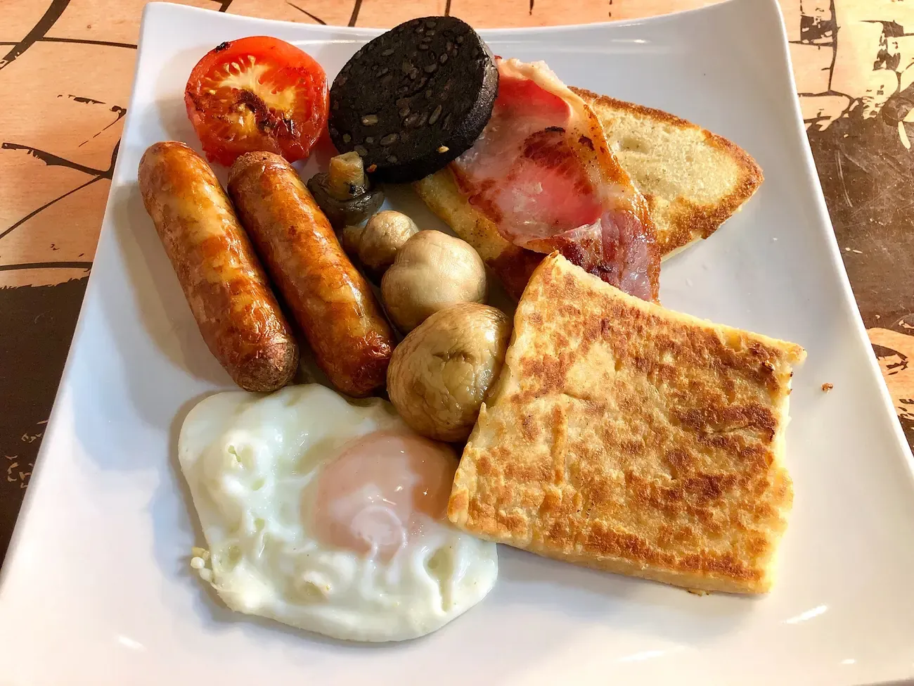 An Ulster fry of sausage, bacon, egg and farl on a plate in Northern Ireland