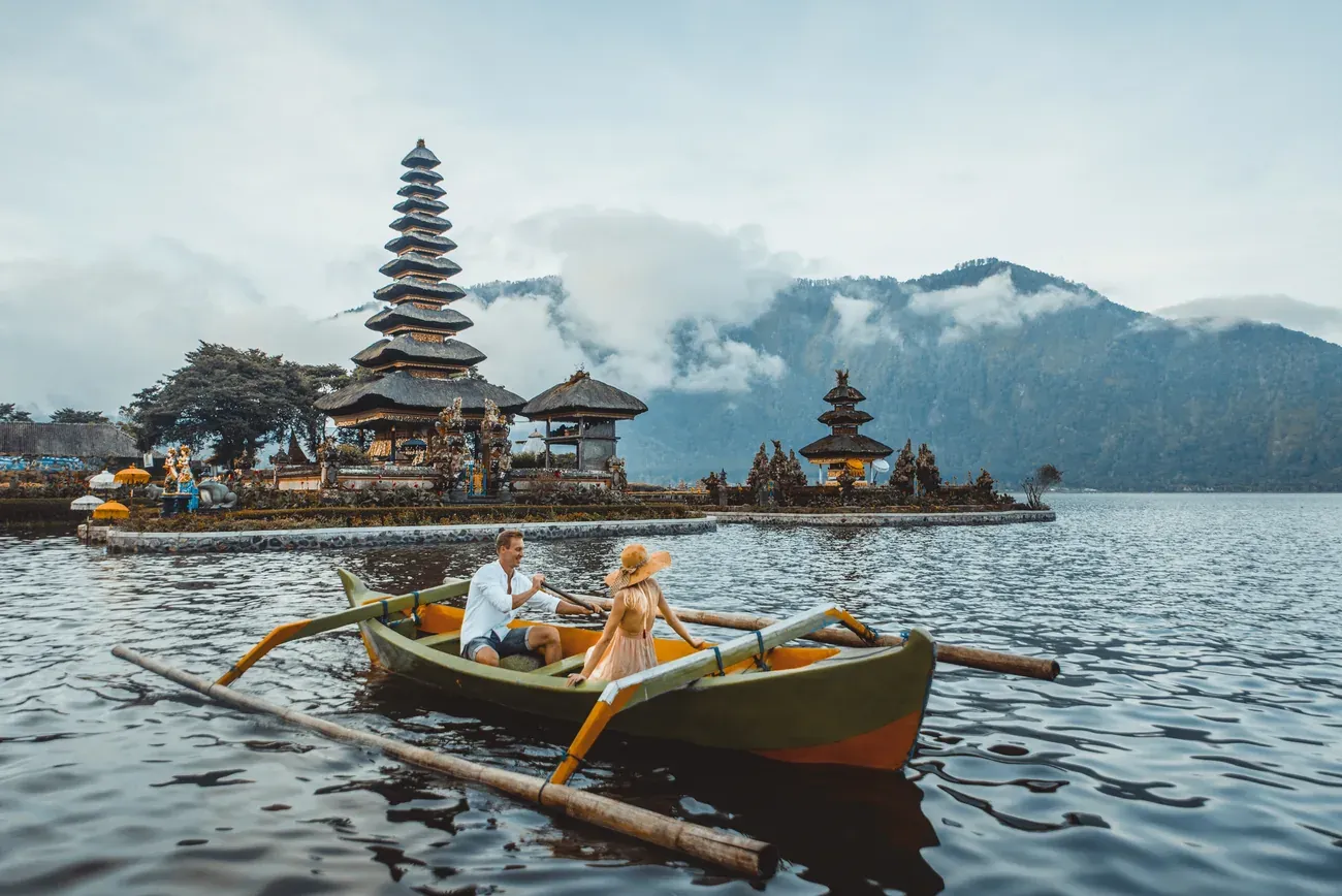 A couple row boating near the Ulun Danu Beratan lake temple in Bali