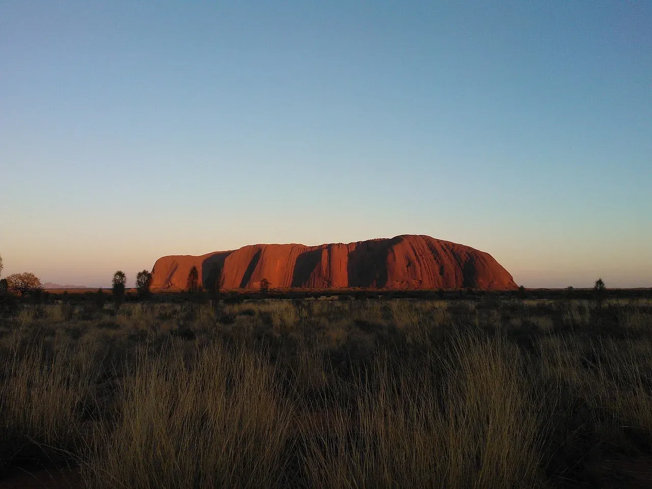Uluru silhouetted at dawn in Uluru-Kata Tjuta National Park