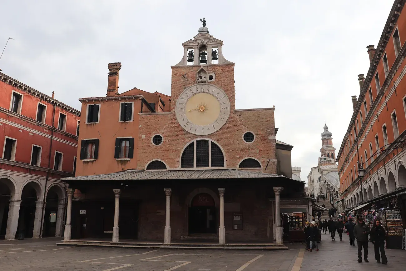 The brick facade of San Giacomo di Rialto with its large 15th-century clock and bell turret in Venice