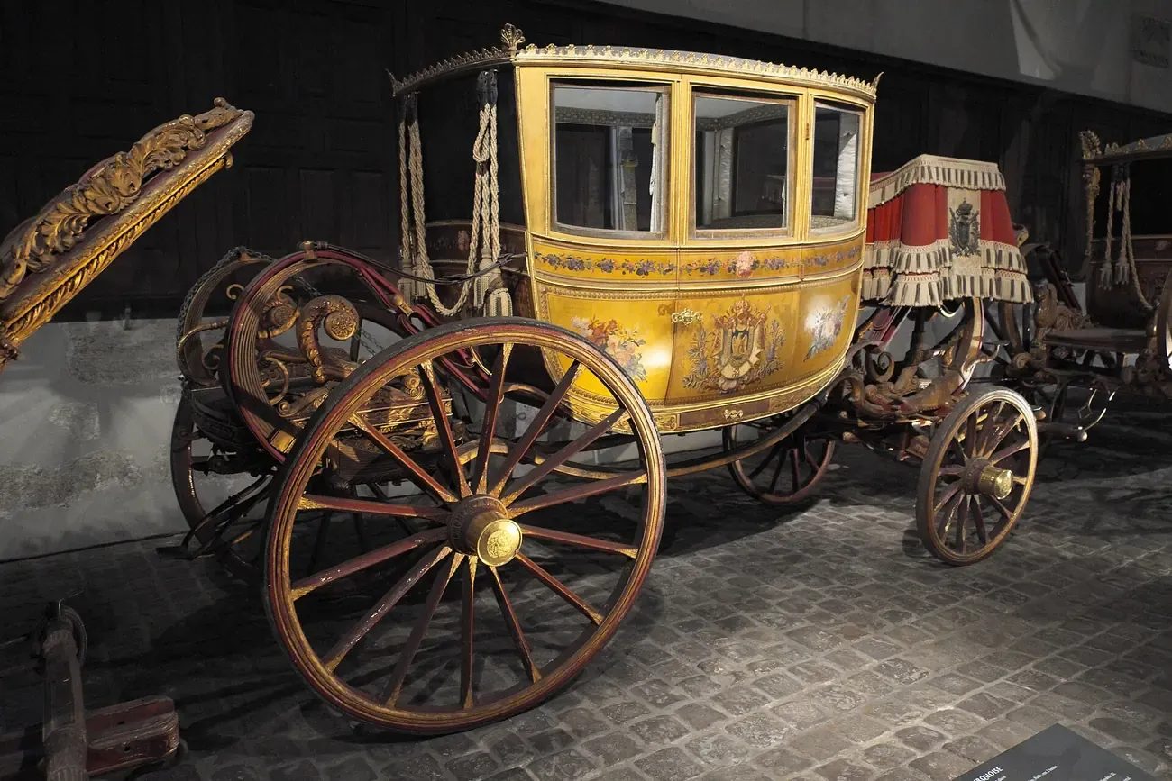 A gilded eighteenth-century ceremonial coach on display inside the Galerie des Carrosses in the Grande Ecurie of Versailles