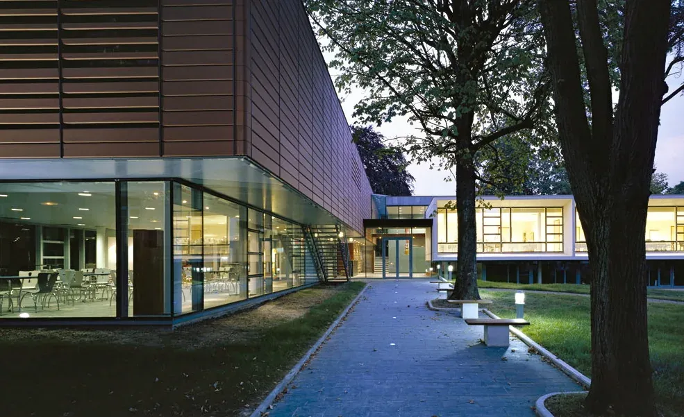 The glazed modern building of the ISIPCA campus that houses the Osmothèque perfume archive in Versailles, lit at dusk