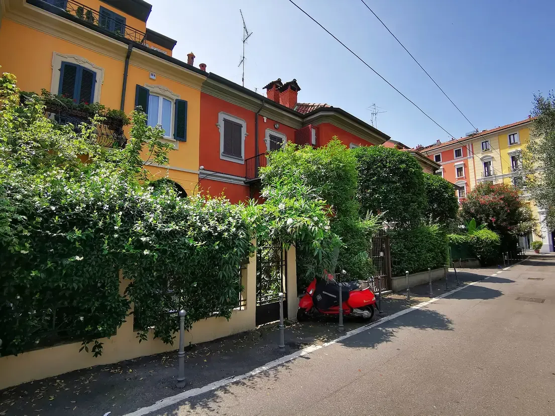 Rows of pastel-coloured houses with hedged gardens on Via Abramo Lincoln in Milan