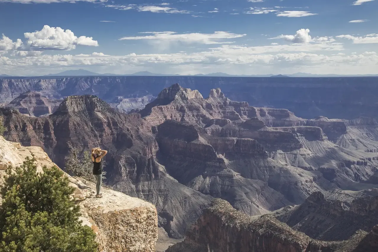 A visitor standing on an overlook above the Grand Canyon in Arizona