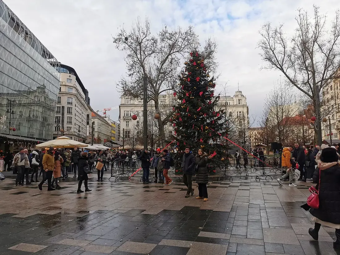 The Christmas fair on Vörösmarty tér in Budapest, with a decorated Christmas tree, stall umbrellas and visitors on the square