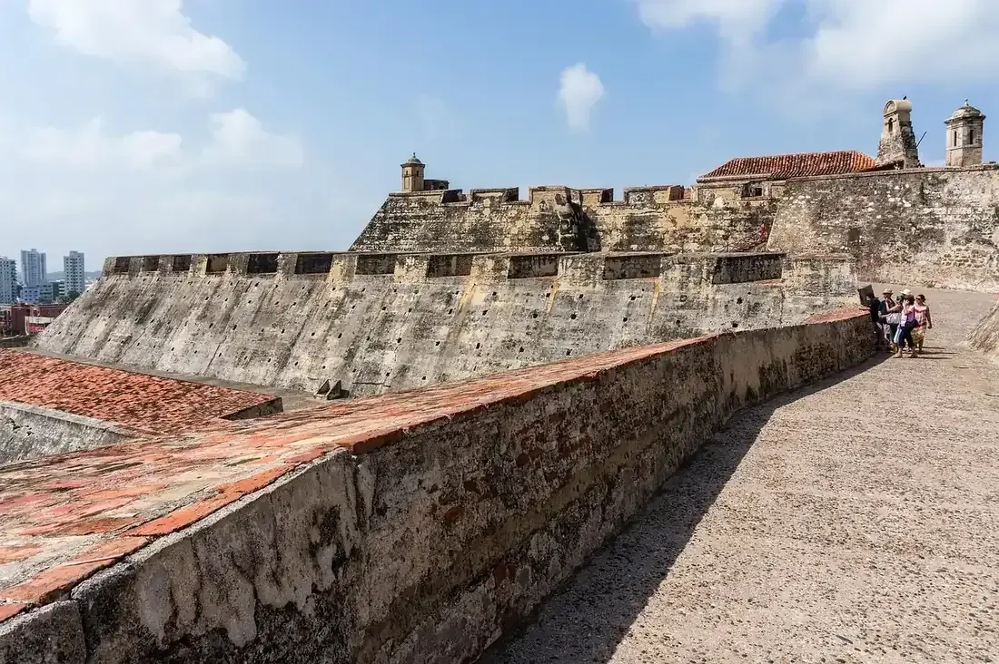 Visitors on the walls of the Castillo San Felipe de Barajas under the Colombian flag